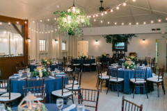beach pavilion with blue table rounds and greenery on tables and on chandelier