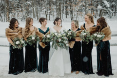 bride with six bridesmaids all holding bouquets with white and green floral arrangements.