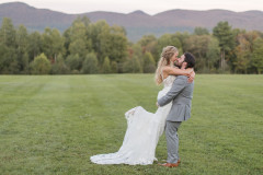 bride and groom kissing in front of sunset colored mountainscape.