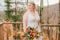 photo of bride holding fall themed bouquet on deck of guest house