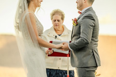 bride and groom holding hands while officiant speaks