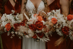 photo of bridal bouquets. bouquets are red, orange, white, with pampas grass included.