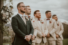 photo of groom in green suit standing at the forefront with four groomsment to his right in tan suits.