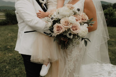 couple close up with child and floral arrangement with pink and white flowers.