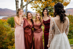 four bridesmaids in red themed dresses at a first look at bride in white long sleeve gown.