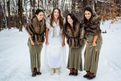 bride with three bridesmaids with green lifting dresses to knees to show winter boots