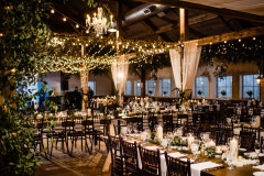 event barn featuring greenery and lights with farmhouse tables.