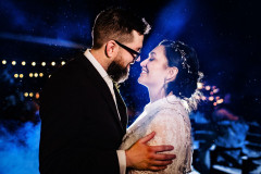 bride and groom holding each other with blue and white lights behind