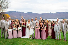 bride and groom standing in the middle of the photo with wedding party surrounding them in red themed attire.