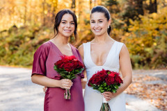 red floral bouquets being held by bride and bridesmaid