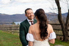 bride and groom looking at each other during a first look in front of a wooden fence with a mountain landscape in the background.