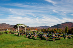 fall wedding knoll featuring farmhouse benches and mountains in background.