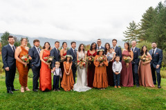 bride and groom in middle with wedding party in blue and oranges