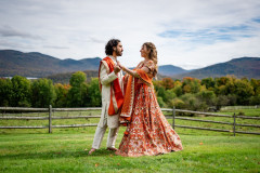 bride and groom in front of wooden fence with mountain scape in the background.