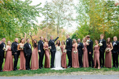 wedding party photo with bride and groom i middle, and bridesmaids and groomsmen on either side of them cheering.