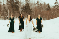 bride in white and bridemaids in green walking towards camera