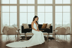 bride sitting on table with windows behind showing snowy background.