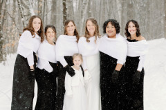 bride with bridal party standing in the snow.