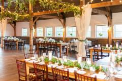event barn with rafters covered in jackson vine, beams with drapery and table settings.