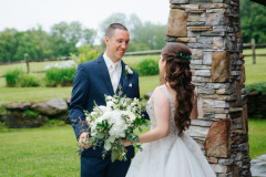 photo of bride and groom during a first look photo by a rock pillar with meadows behind.