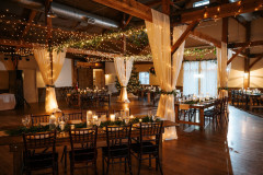 event barn with drapery and lights with farmhouse tables scattered throughout space.