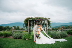 bride and groom at the wedding knoll kissing with the green mountains in vermont behind them.