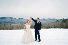 bride and groom in front of mountain scape holding hands.