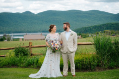 bride and groom standing at wooden fence overlooking mountains and lake.