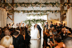 bride and groom kissing at the end of the aisle surrounding by guests.