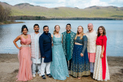 photo of bride and groom with family members in front of lake in indian style garments