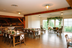 loft set up for a reception in the event barn at mountain top resort featuring farmhouse tables with chivari chairs, and a lounge set up by the windows.