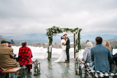 winter wedding arbor on the terrace featuring bride and groom kissing in front of guests.