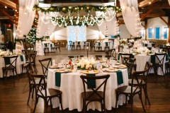 interior of barn setup with drapery, white table cloths, and round tables for a wedding reception.