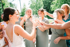 bride and wedding party clinking glasses of champagne together.