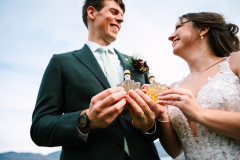 bride and groom looking at each other smiling while holding maple syrup in front of camera