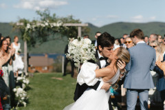 bride and groom sharing a kiss down the center aisle of the ceremony site after tying the knot. 