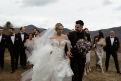 bride and groom walking towards camera with wedding party behind them. 