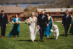 bride and groom in center of photo walking towards camera with wedding party behind them.