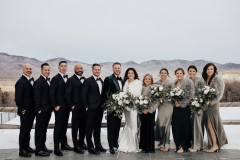 bridesmaids and groomsmen in a line with floral bouquets with mountain scape in background.