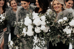 close up of floral arrangements for winter wedding featuring women in background smiling.