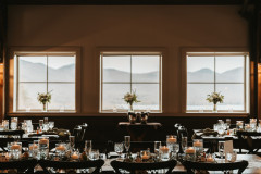 event barn showcasing windows with mountain scape in background and bouquets on window sills.