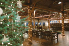 event barn set up for a small intimate wedding reception with a holiday tree featured in the corner.