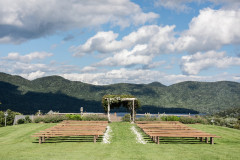 wedding knoll featuring farmhouse benches on either side of arbor leading to arbor and petals in aisle to guide the way.