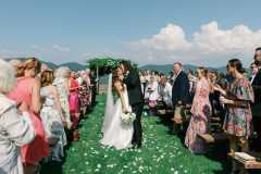 bride and groom kissing with wedding knoll behind them surrounded by guests.