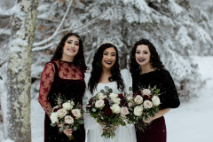 bride and two bridesmaids holding floral bouquets.