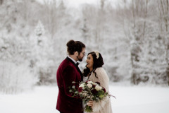 bride and groom embracing with winterscape behind them.