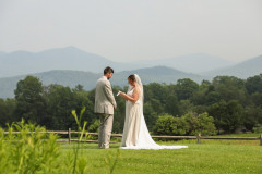 bride and groom exchanging vows together with mountain scape behind them.