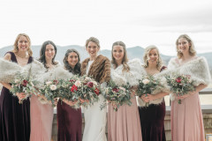 bride in middle with three bridesmaids on both sides of her, all holding wedding bouquets.