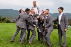 groom being lifted by groomsmen while looking at camera. 