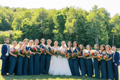 two brides in center with bridesmaids and bridesmen on ends in blue